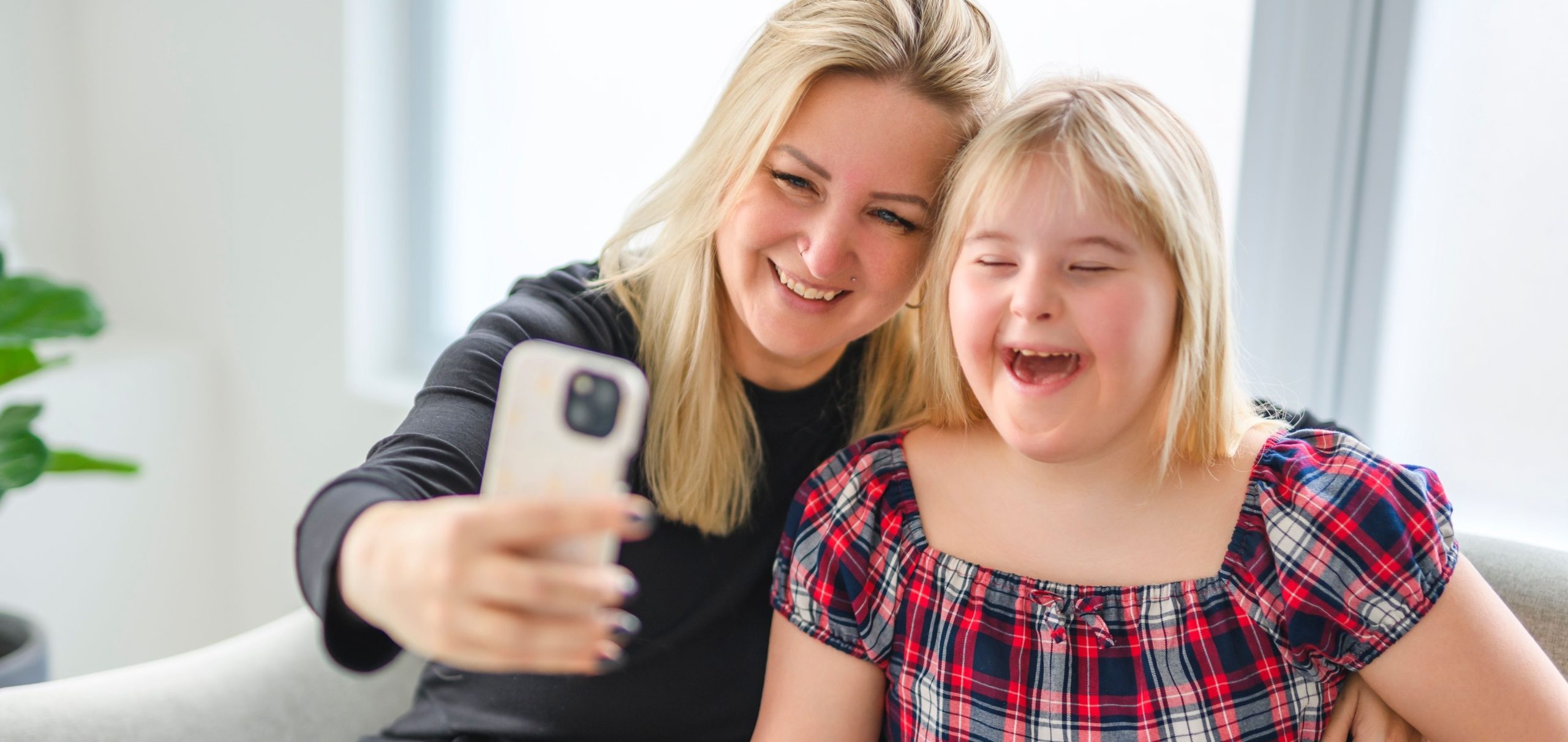 Mother and daughter smiling in front of a camera