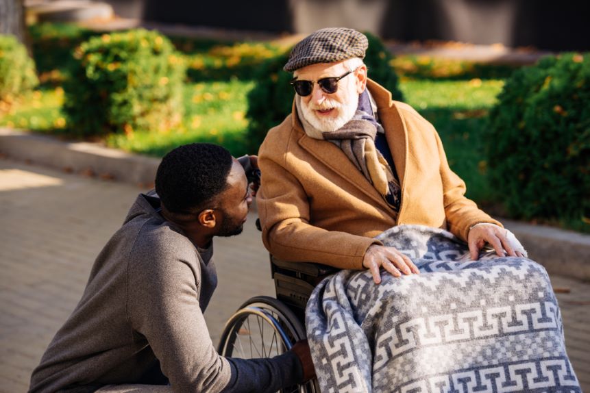 male carer talking to a gentleman in a wheelchair