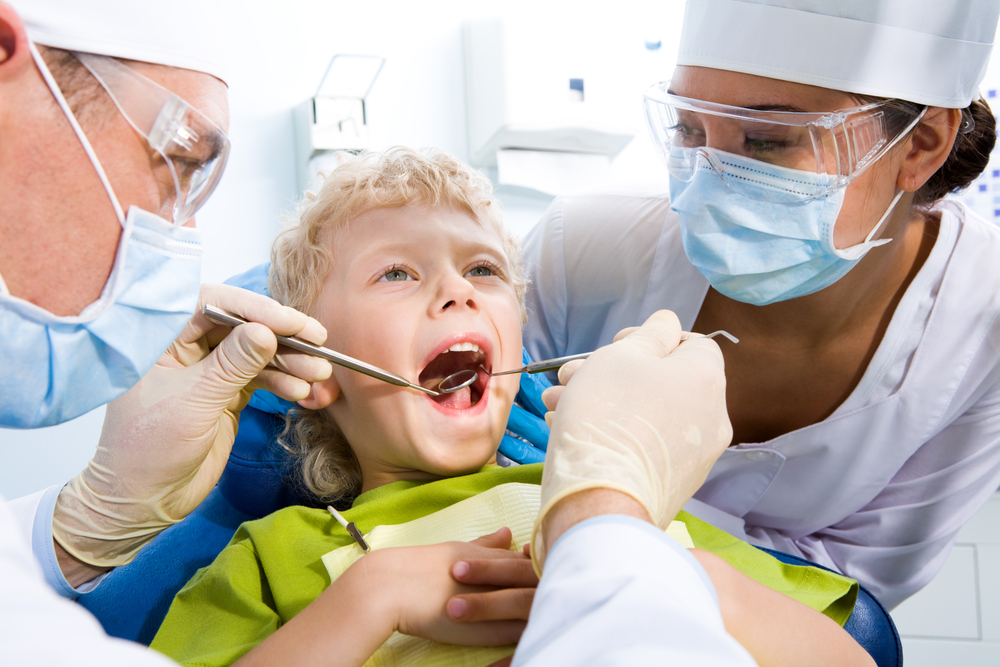 Dental Nurse helping while Little Boy is inspected by dentist