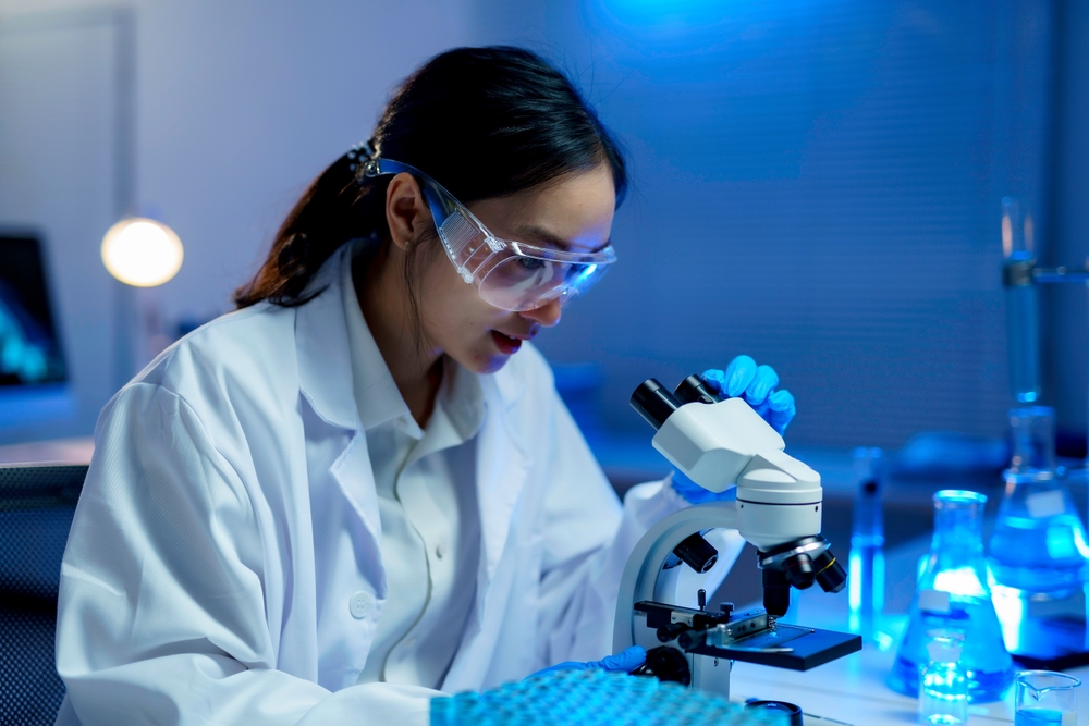 Female Biochemist Wearing Lab Coat And Protective Glasses